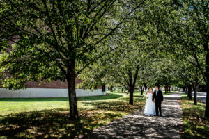 bride and groom walking along tree covered sidewalk